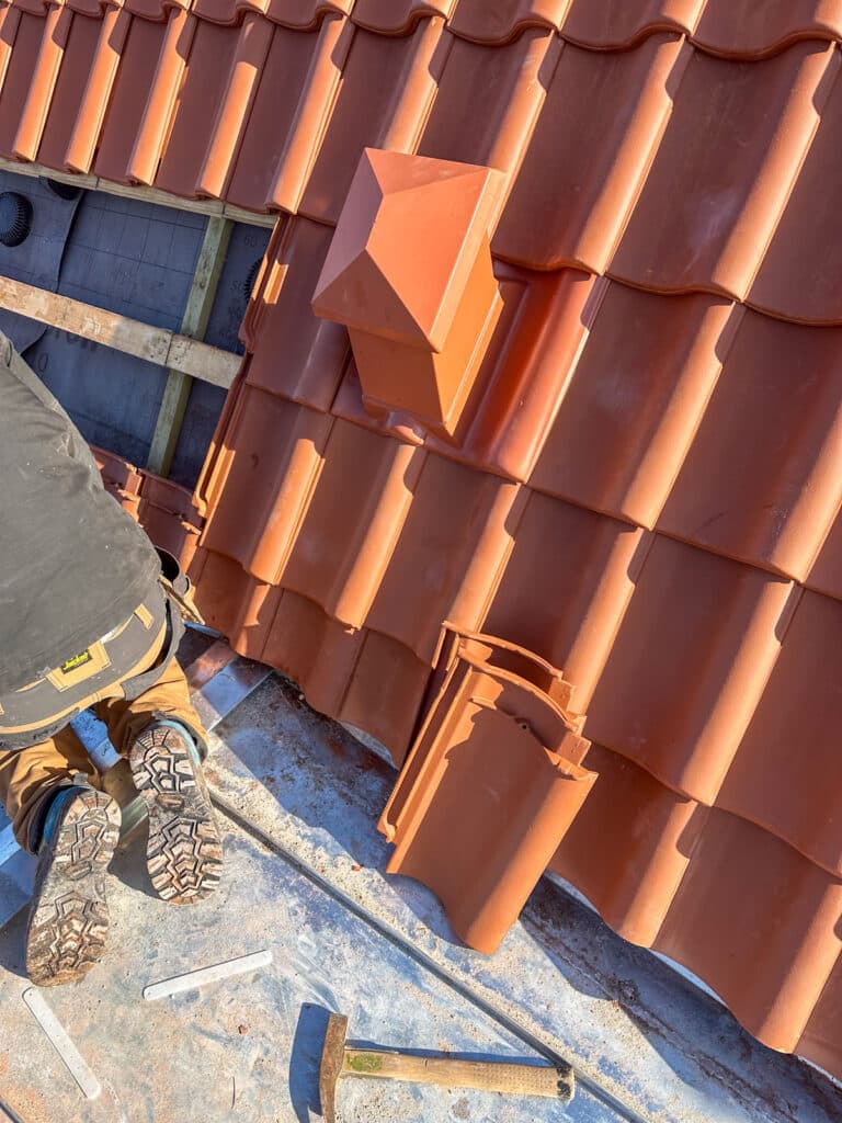 Tømrer lægger tegl omkring ventilationshætten på nyt tag i Rødovre
