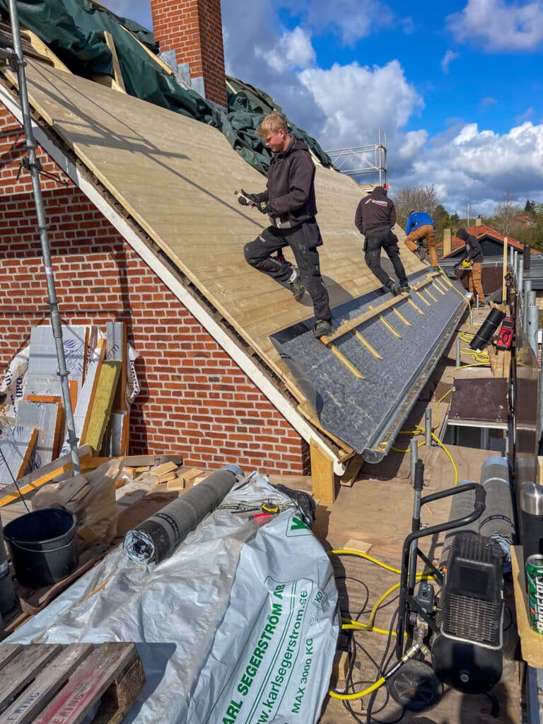 Tømrere lægger undertag på brædder ved tagrenovering i Ballerup
