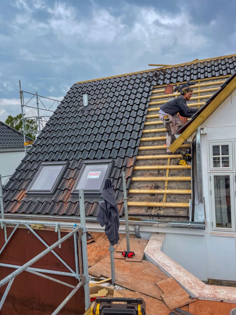 Tømrer lægger sorte glaserede tegl ved kvisten på tag i Charlottenlund